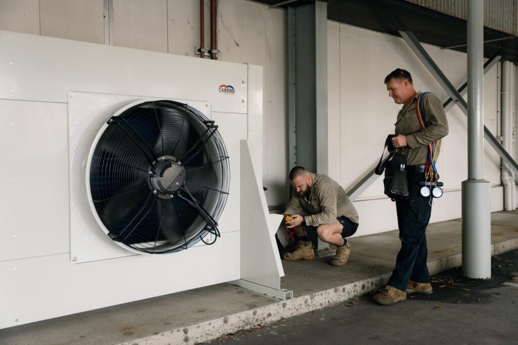 Technician working on a large industrial condenser fan unit